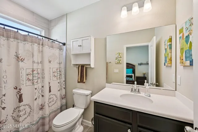 a bathroom with a sink a toilet a mirror and shower curtain