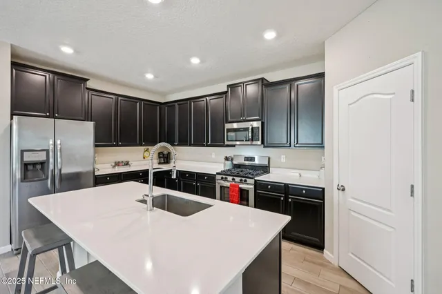 a kitchen with stainless steel appliances a sink stove refrigerator and cabinets