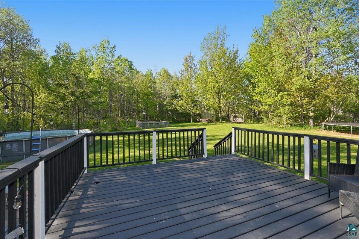 47 Amy Lane Esko, MN 55733 - Photo 4 of 33 Expansive outdoor deck with dark-stained wood planks and black railings, overlooking a large grassy yard