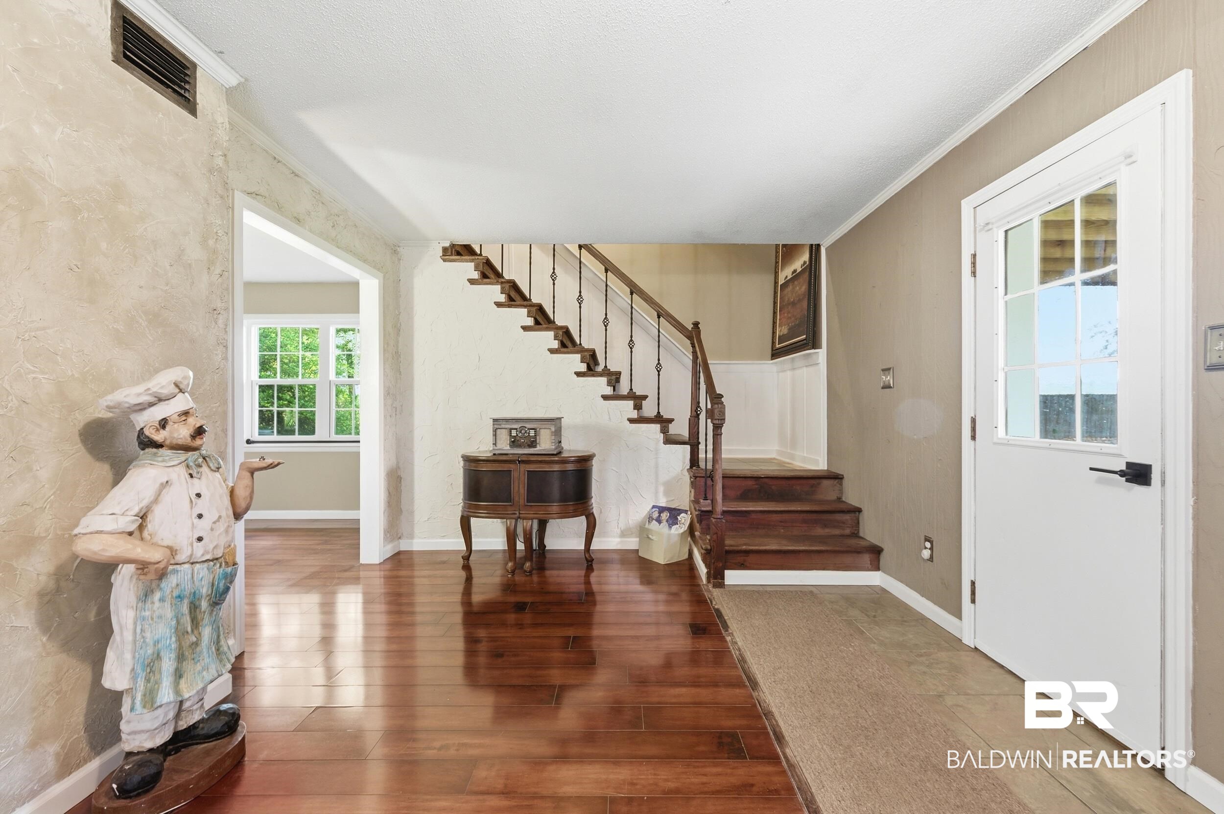 51620 Robert White Road Bay Minette, AL 36507 - Photo 24 of 81 Entryway featuring rich wood-finish flooring, a staircase with dark wood treads and wrought iron balusters, a paneled door with glass inserts, and a textured wall finish