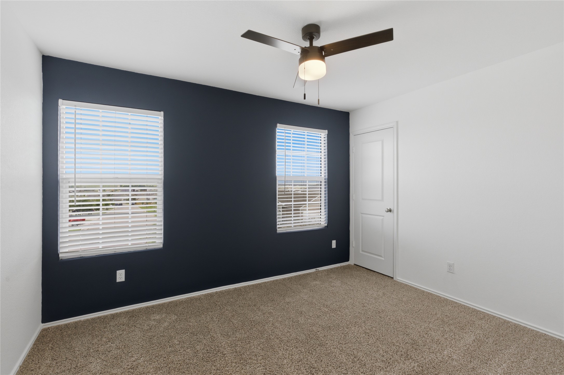 116 Night Riders Way Jarrell, TX 76537 - Photo 30 of 40 Bedroom featuring a dark accent wall, two windows with white blinds, a ceiling fan with integrated lighting, and neutral carpet flooring