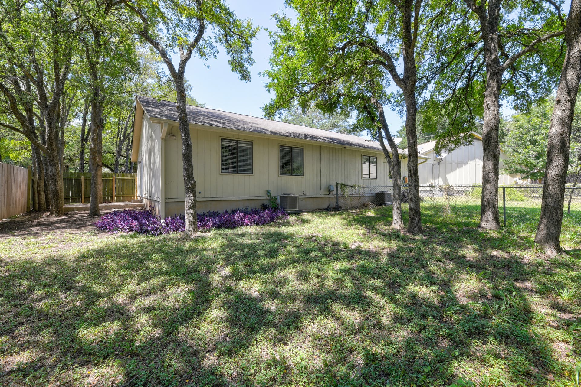 12603 Teague Trail, Unit B Austin, TX 78729 - Photo 14 of 14 a backyard of a house with table and chairs and large trees