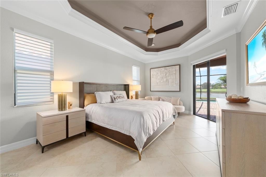 12692 Kinross Lane Naples, FL 34120 - Photo 19 of 47 Tray ceiling with crown molding, ceiling fan, large format tile flooring, sliding glass door, and window with blinds