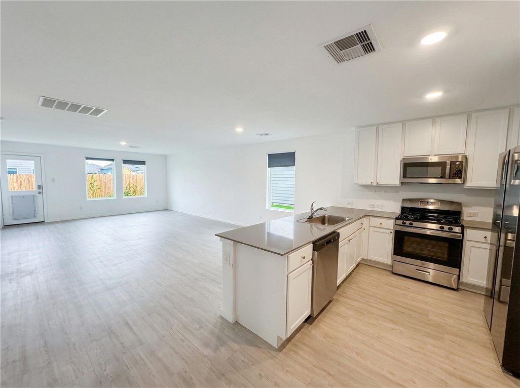 9201 Wilde Way Corpus Christi, TX 78410 - Photo 2 of 21 a kitchen with stainless steel appliances granite countertop a stove top oven a sink with wooden floors and cabinets