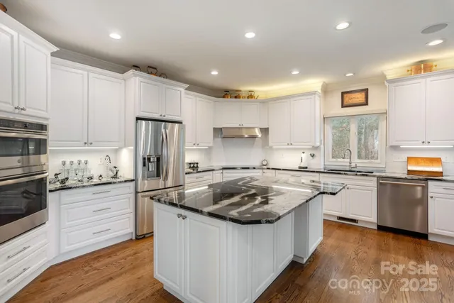 a kitchen with granite countertop a sink stainless steel appliances and cabinets