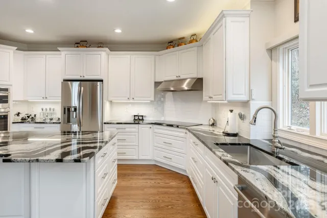 a kitchen with kitchen island granite countertop a sink stainless steel appliances and cabinets