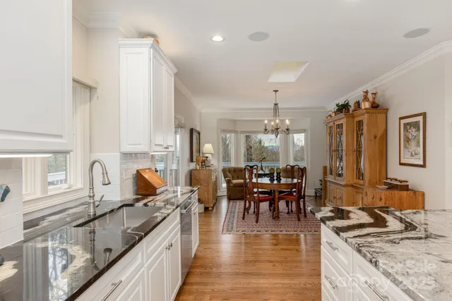 a kitchen with stainless steel appliances granite countertop a stove top oven a sink a dining table and chairs with wooden floor