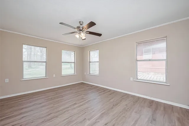 a view of an empty room with a window and wooden floor