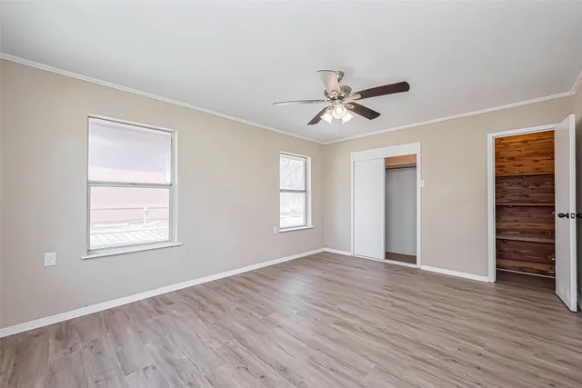 a view of empty room with wooden floor and ceiling fan