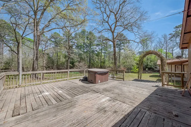 a view of a deck with large trees and wooden fence