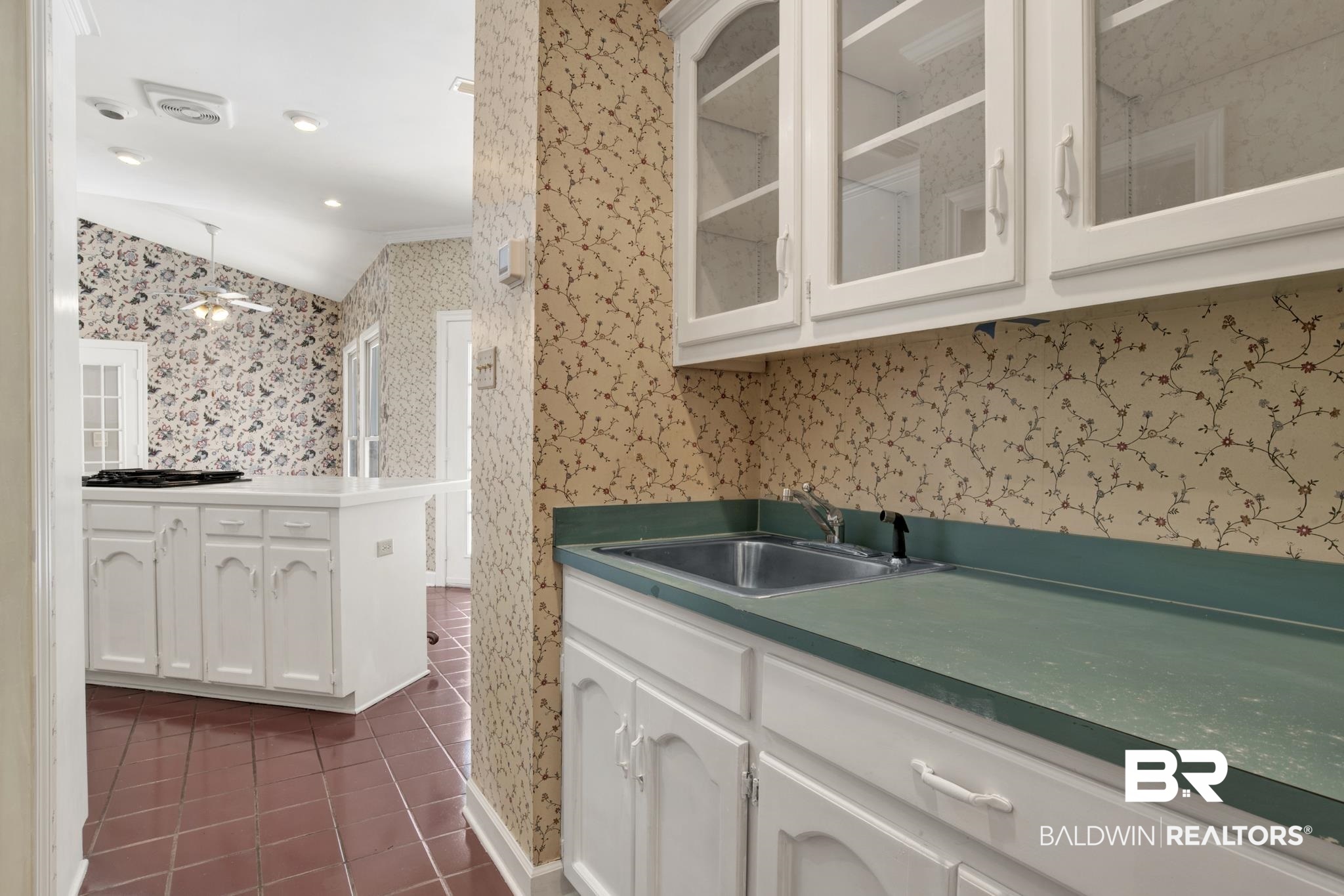 6805 Hunters Court Mobile, AL 36695 - Photo 17 of 37 Kitchen featuring a sink, wallpapered walls, dark tile patterned flooring, white cabinetry, and lofted ceiling
