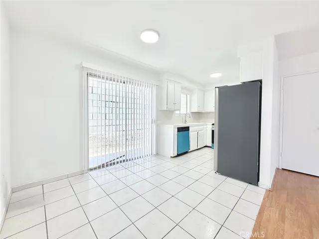 a large white kitchen with white cabinets and refrigerator