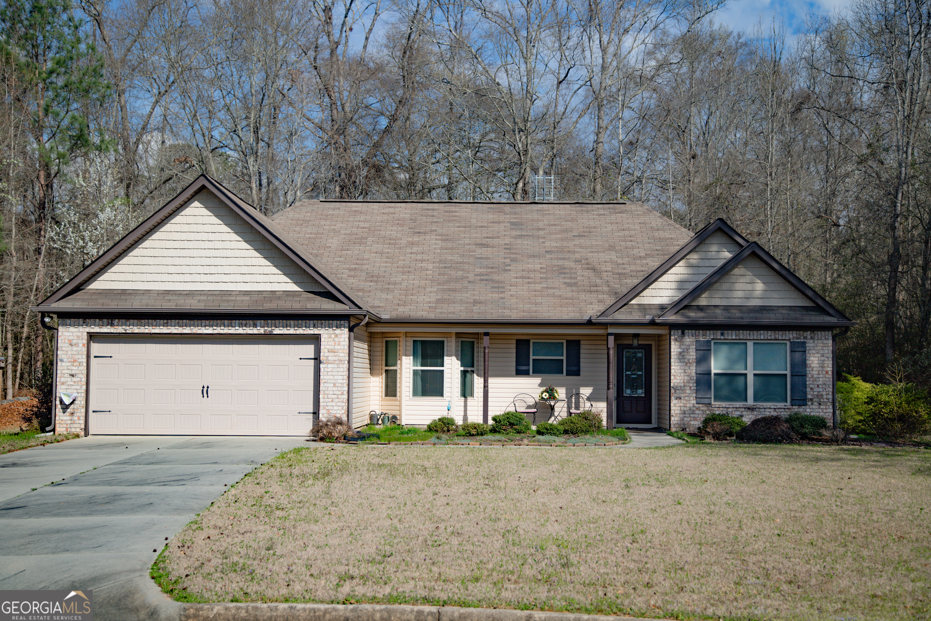 front view of a house with a dry yard and large trees