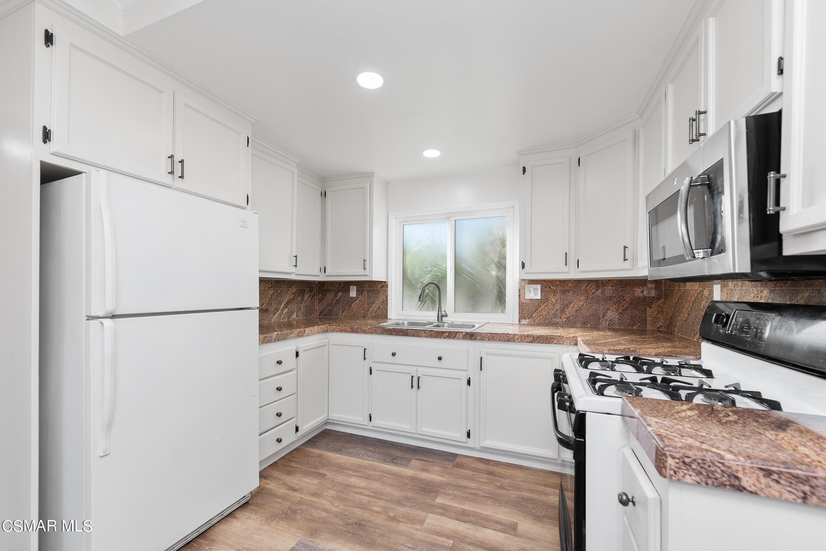 2181 Rhoda Street Simi Valley, CA 93065 - Photo 11 of 36 a kitchen with granite countertop a refrigerator stove a sink and white cabinets