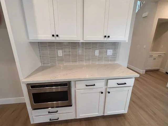 a kitchen with granite countertop white cabinets appliances and a sink