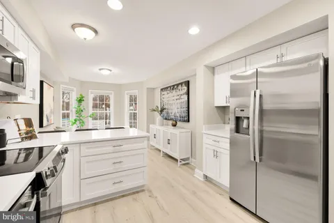 a kitchen with white cabinets and refrigerator