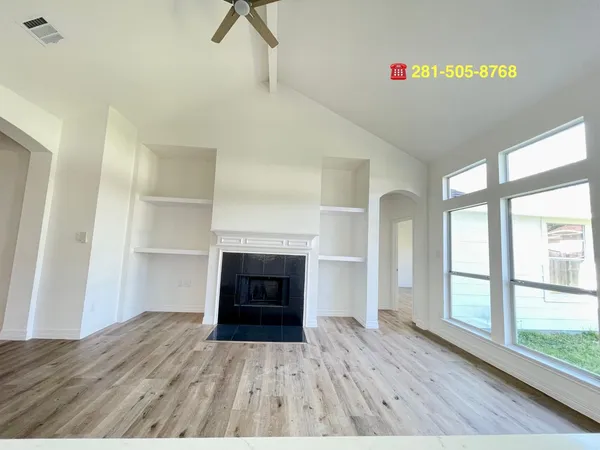 a view of empty room with wooden floor and fireplace