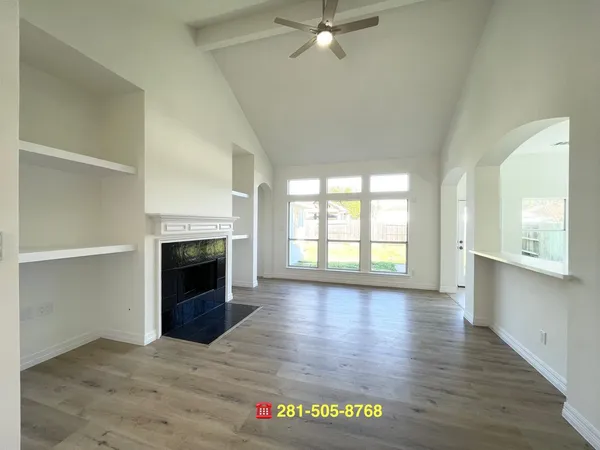 an empty room with wooden floor fireplace and windows