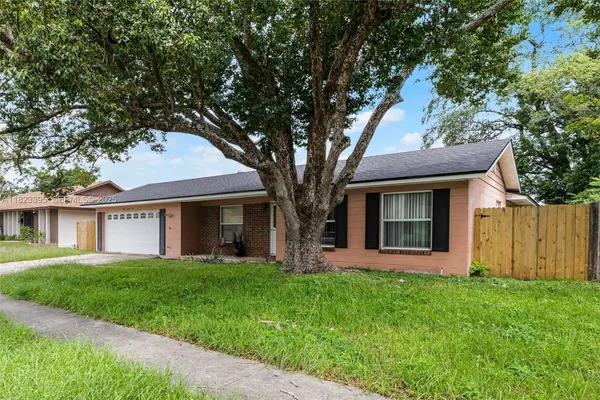 a front view of a house with a yard and large trees