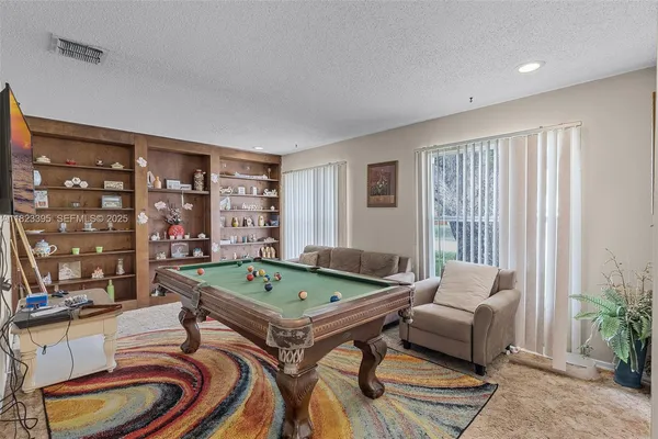 a living room with furniture a pool table and a large window