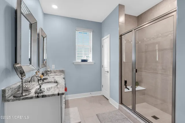 a bathroom with a granite countertop sink a mirror and a shower