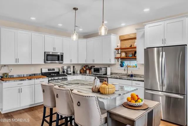a kitchen with a refrigerator a stove a sink and chairs