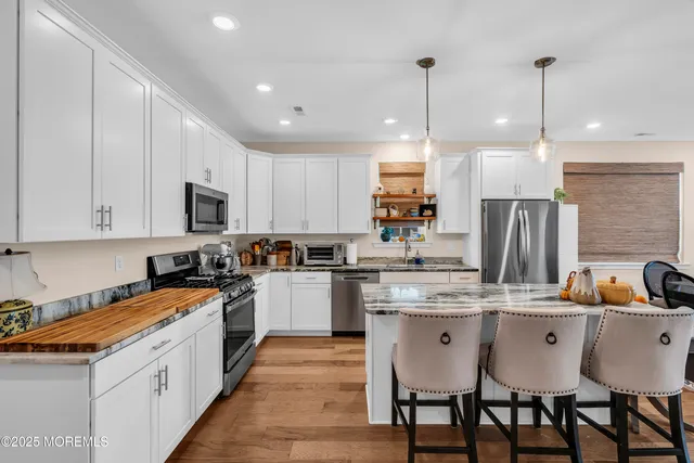 a kitchen with stainless steel appliances granite countertop a sink a stove a refrigerator and chairs