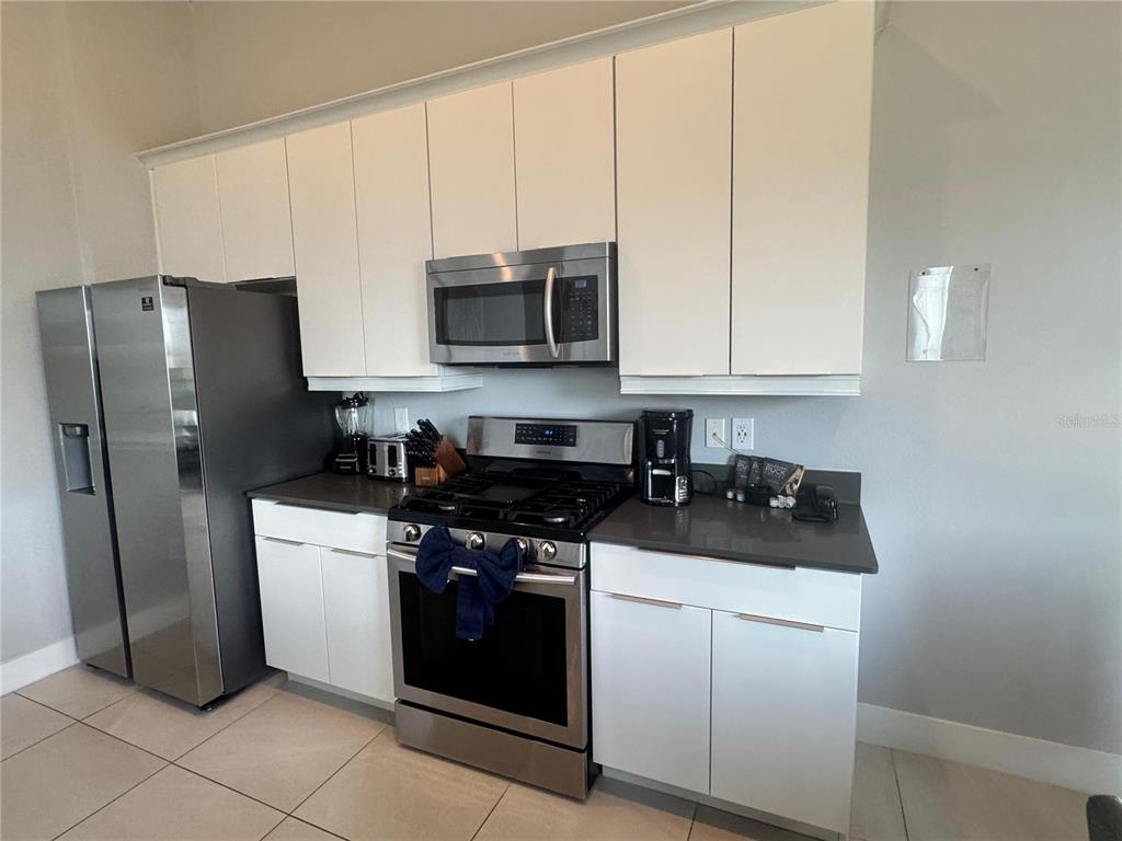 7770 Sandy Ridge Drive, Unit 210 Reunion, FL 34747 - Photo 6 of 42 a kitchen with stainless steel appliances granite countertop a stove a refrigerator and a microwave