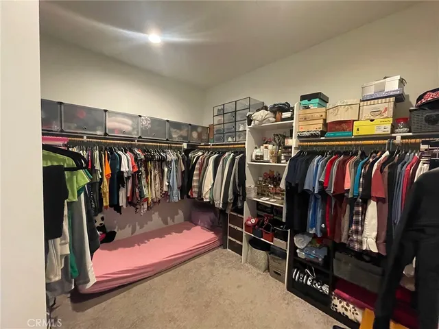 a view of walk in closet with clothes and shoes