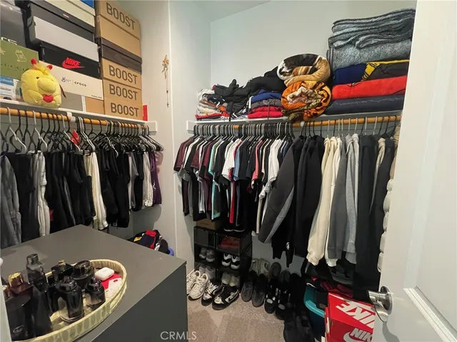 a view of walk in closet with clothes and shoes