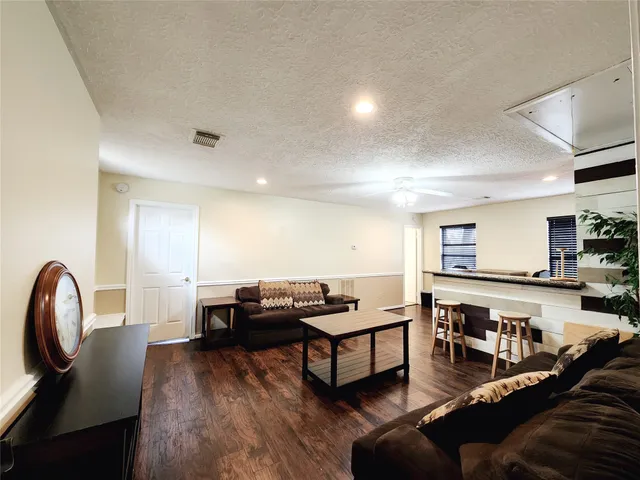 a living room with stainless steel appliances furniture a rug and a kitchen view