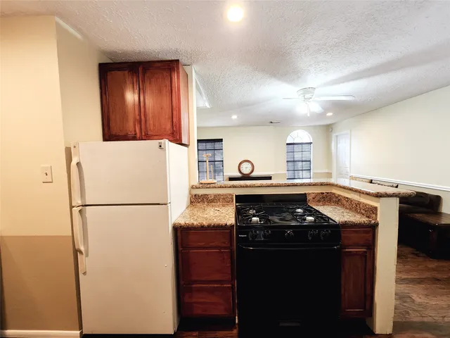 a kitchen with granite countertop a refrigerator a stove and a sink