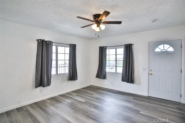 a view of an empty room with a window and wooden floor