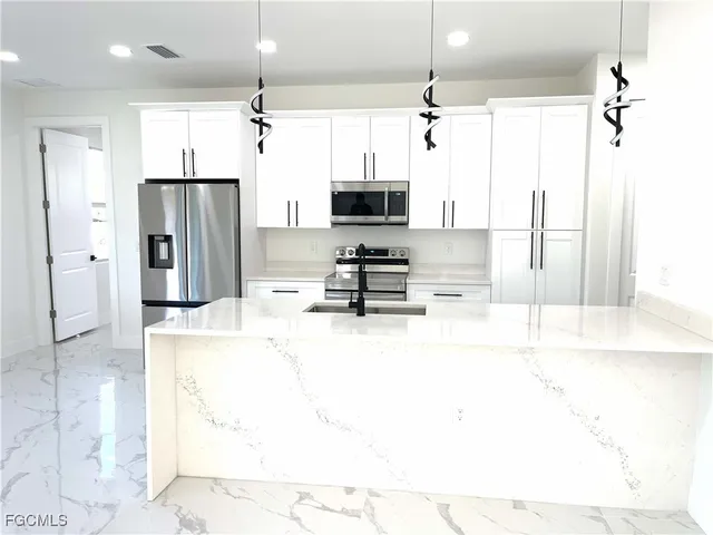 a kitchen with stainless steel appliances kitchen island granite countertop a refrigerator and a stove top oven