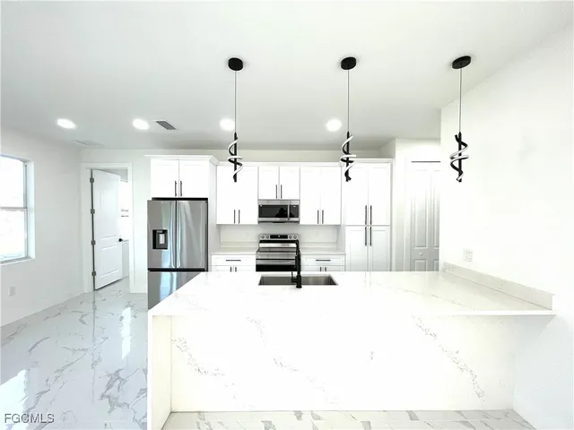 a kitchen with stainless steel appliances kitchen island granite countertop a refrigerator a oven a sink with a countertop and chairs