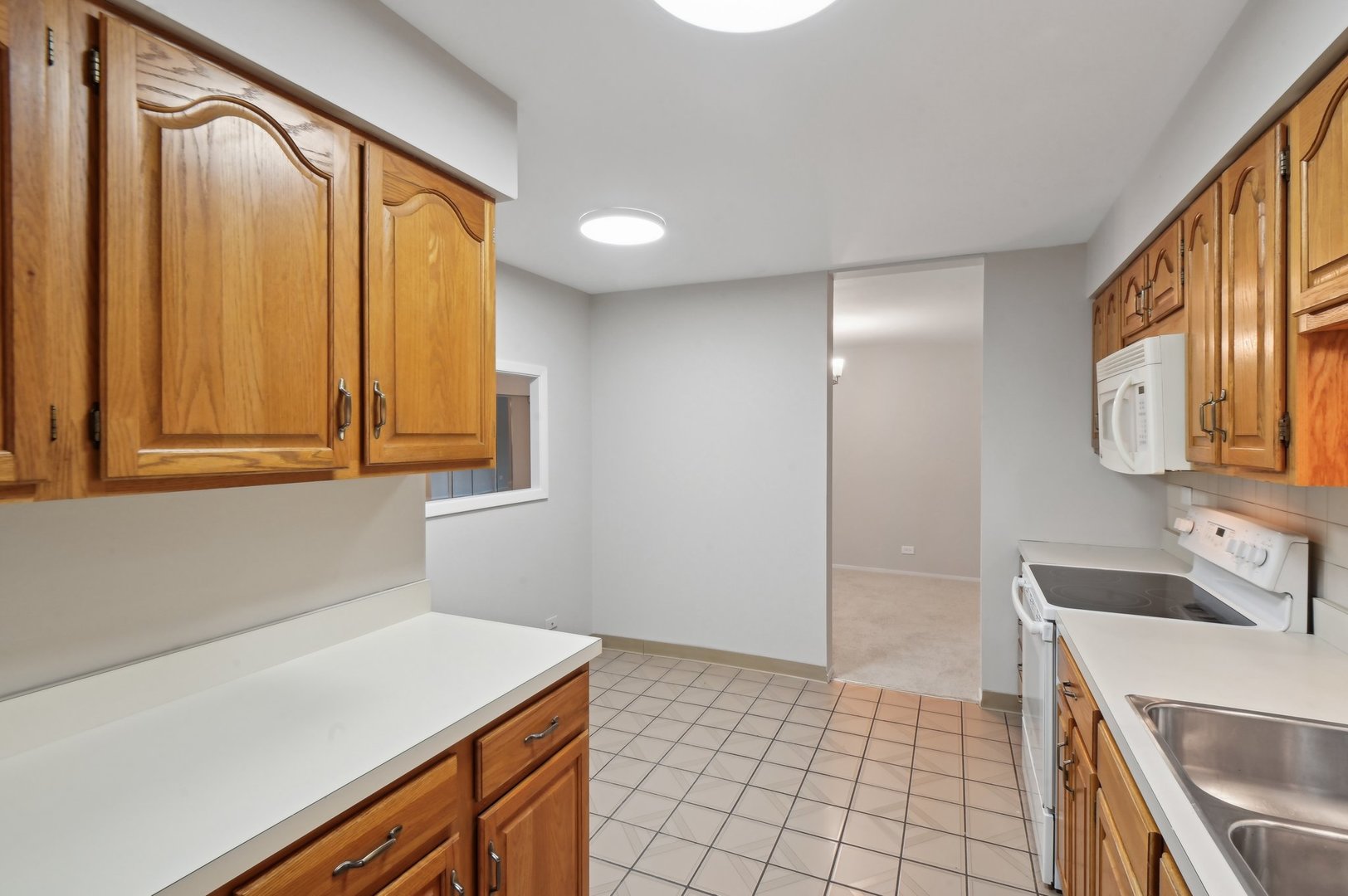 1615 East Central Road, Unit 121C Arlington Heights, IL 60005 - Photo 10 of 23 a room with a refrigerator and a sink
