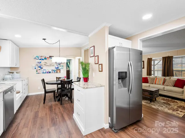 a kitchen with stainless steel appliances a refrigerator a stove top oven a dining table and chairs with wooden floor