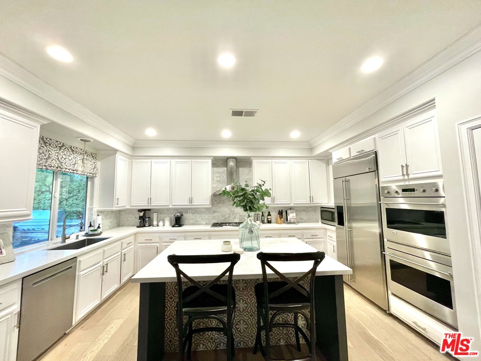26810 Kendall Lane Stevenson Ranch, CA 91381 - Photo 20 of 44 a kitchen with a table chairs microwave and cabinets