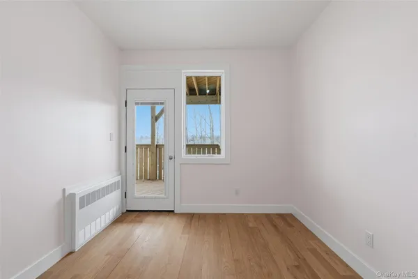 a view of an empty room with wooden floor and a window