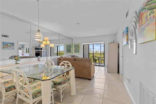a dining table chairs in a living room and a chandelier