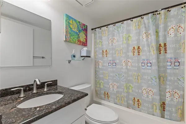 a bathroom with a granite countertop sink a toilet and shower curtain