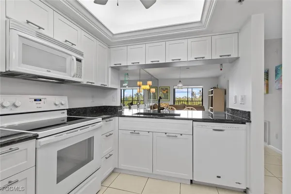 a kitchen with granite countertop white cabinets and white appliances