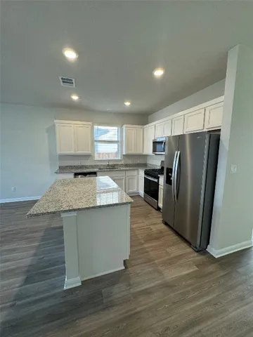 a kitchen with stainless steel appliances granite countertop a refrigerator a sink a stove and oven