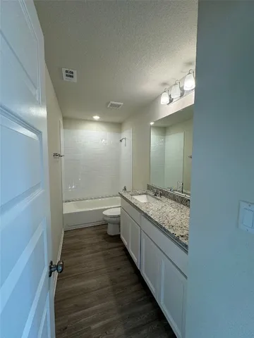 a bathroom with a granite countertop sink a toilet and shower