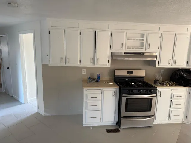 a kitchen with stainless steel appliances granite countertop white cabinets and a stove a refrigerator with white countertops