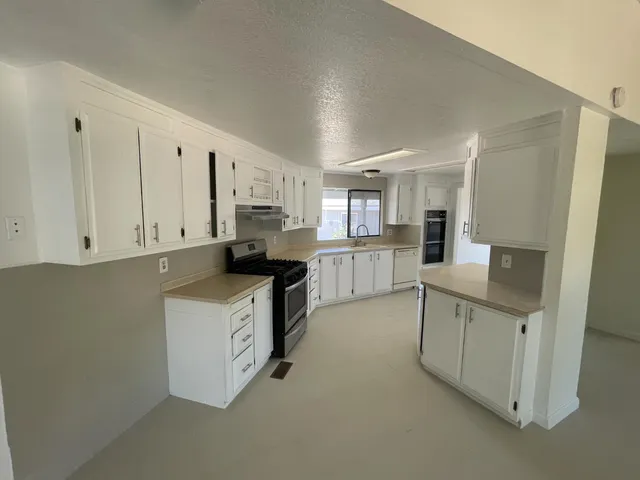 a kitchen with stainless steel appliances a sink a stove a refrigerator cabinets and a window