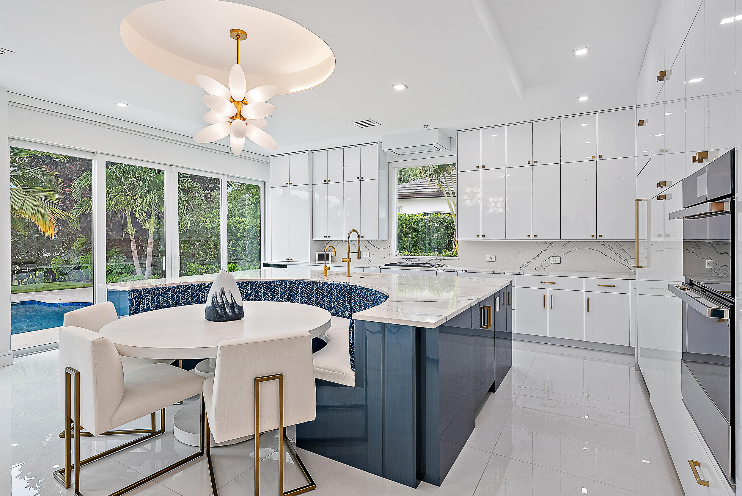 134 Golf Village Boulevard Jupiter, FL 33458 - Photo 11 of 48 a kitchen with stainless steel appliances kitchen island a table chairs in it and white cabinets