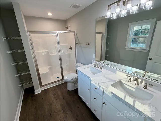 a spacious bathroom with a double vanity sink toilet mirror and a shower
