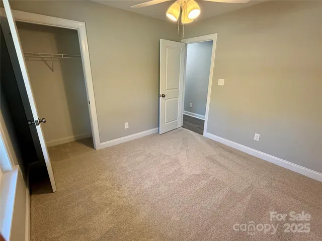 an empty room with closet and a chandelier fan