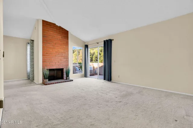 a view of an empty room with a fireplace and a window